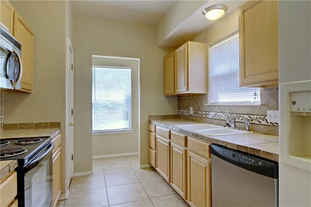 kitchen with stainless steel appliances, sink, light brown cabinets, backsplash, and light tile patterned floors