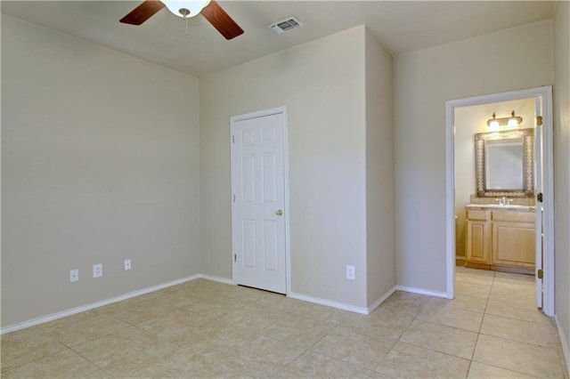 unfurnished bedroom with sink, ensuite bathroom, light tile patterned floors, and ceiling fan