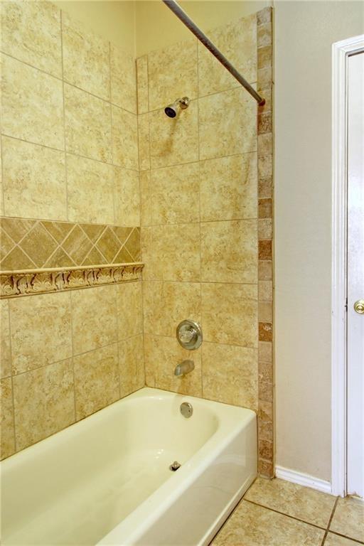 bathroom featuring tile patterned floors, baseboards, and shower / bathtub combination