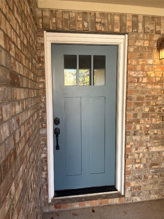 view of exterior entry featuring brick siding