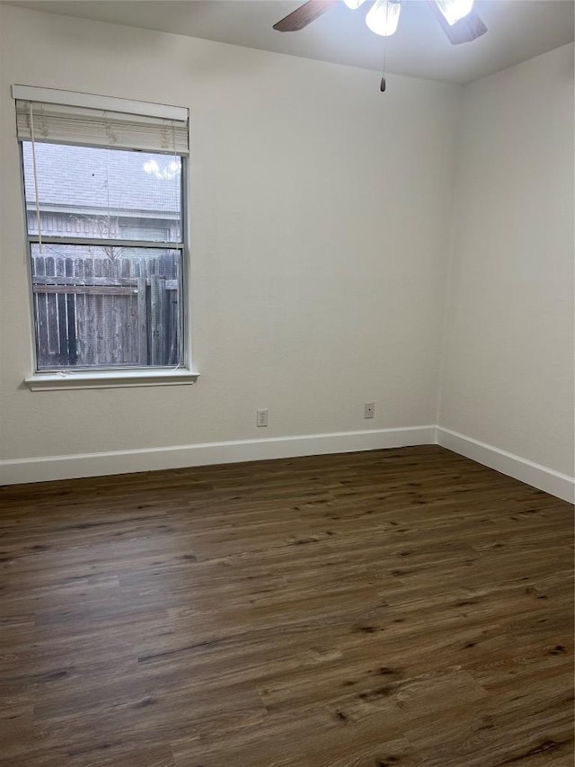 empty room featuring dark wood-type flooring, baseboards, and a ceiling fan