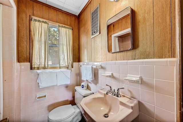 bathroom with sink, backsplash, toilet, and tile walls