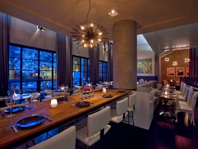 dining room with wood-type flooring, a chandelier, and ornate columns