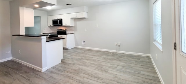 kitchen featuring plenty of natural light, white cabinetry, backsplash, and stainless steel appliances