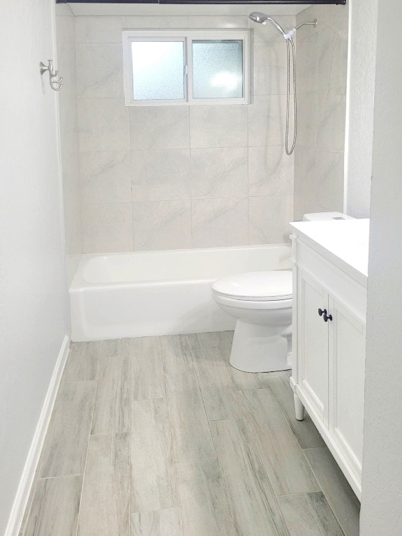 full bathroom featuring vanity, tiled shower / bath combo, and toilet