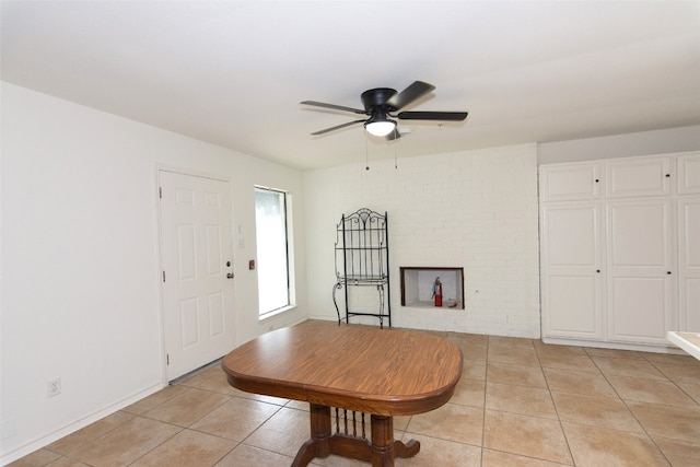 interior space featuring ceiling fan, brick wall, and light tile floors