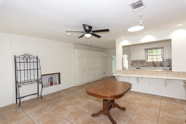 kitchen with kitchen peninsula, white cabinetry, ceiling fan, tasteful backsplash, and a breakfast bar area