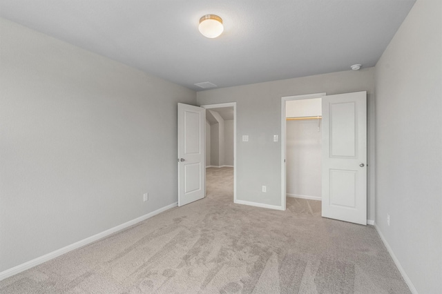 unfurnished bedroom featuring light colored carpet, a closet, and a walk in closet