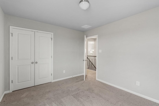 unfurnished bedroom featuring light colored carpet and a closet