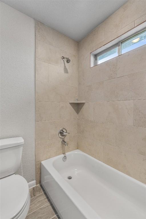 bathroom with toilet and tiled shower / bath combo