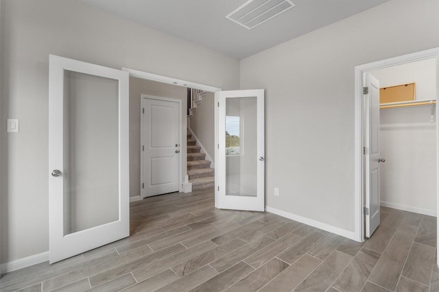 unfurnished bedroom with a closet, french doors, and a walk in closet