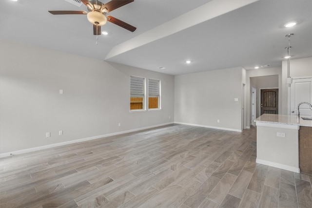 unfurnished living room featuring ceiling fan, sink, and light hardwood / wood-style floors