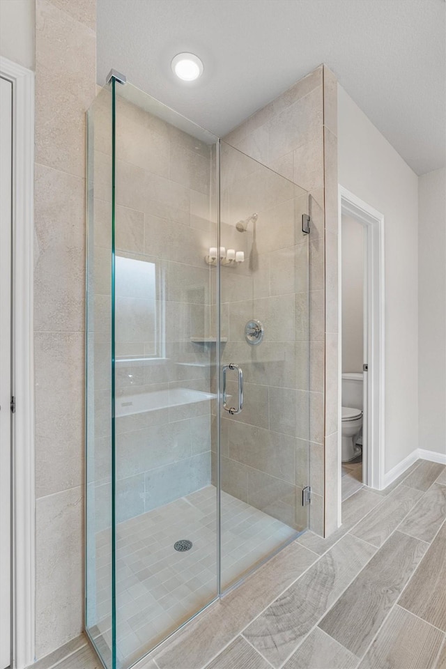 bathroom featuring toilet and a shower with door