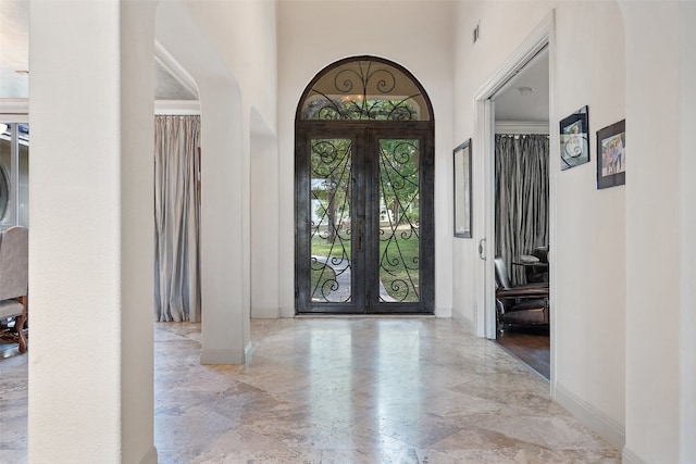 entrance foyer featuring french doors, a towering ceiling, and light tile flooring