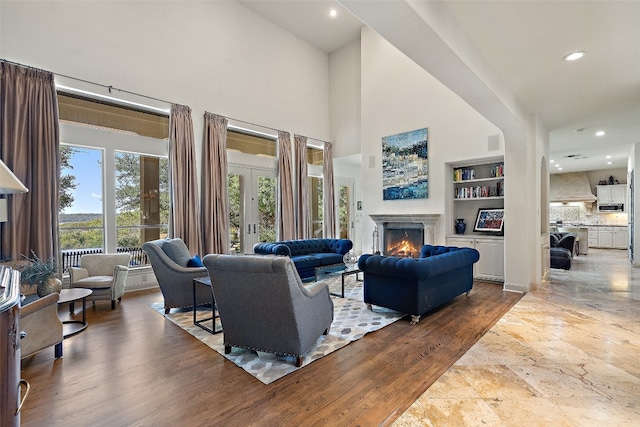 living room featuring a high ceiling, hardwood / wood-style floors, french doors, and built in shelves