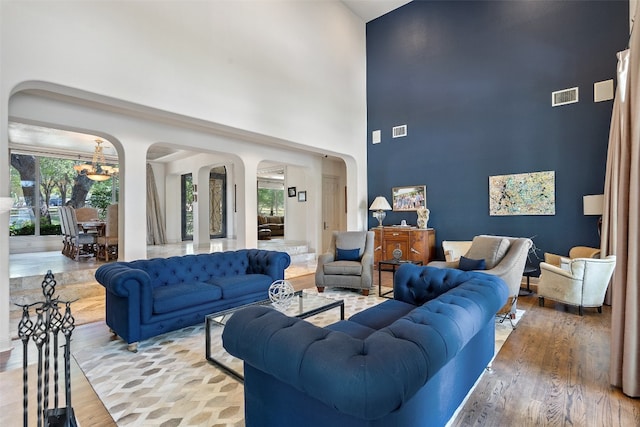 living room with an inviting chandelier, light hardwood / wood-style floors, and a high ceiling