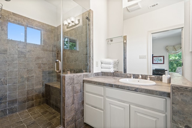 bathroom featuring a shower with shower door and vanity with extensive cabinet space