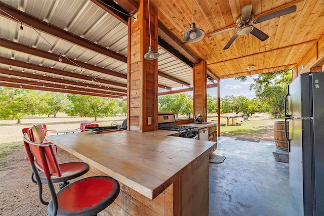 view of patio with area for grilling, ceiling fan, and exterior bar