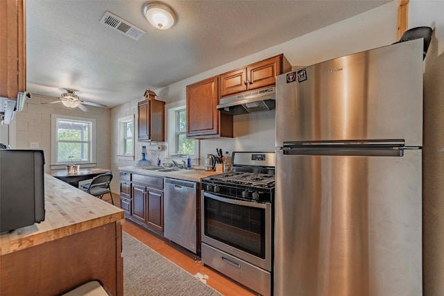 kitchen featuring a textured ceiling, ceiling fan, appliances with stainless steel finishes, and wooden counters