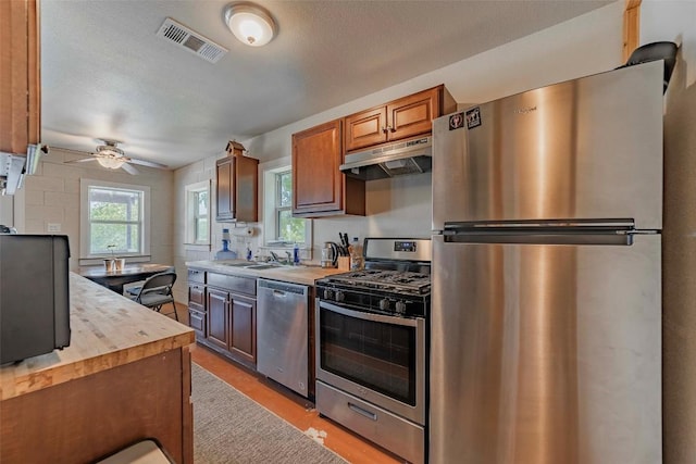 95 Loma Ln, Fredericksburg, TX 78624 - kitchen with appliances with stainless steel finishes, under cabinet range hood, a ceiling fan, light wood-style floors, and wood counters