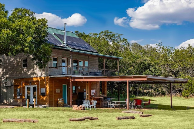 back of property featuring a balcony and a lawn