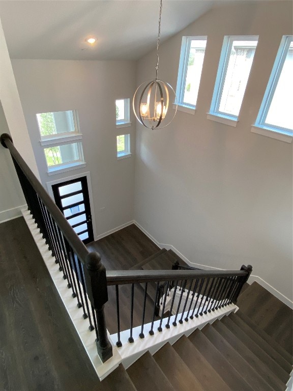 stairs with wood-type flooring, a notable chandelier, and plenty of natural light