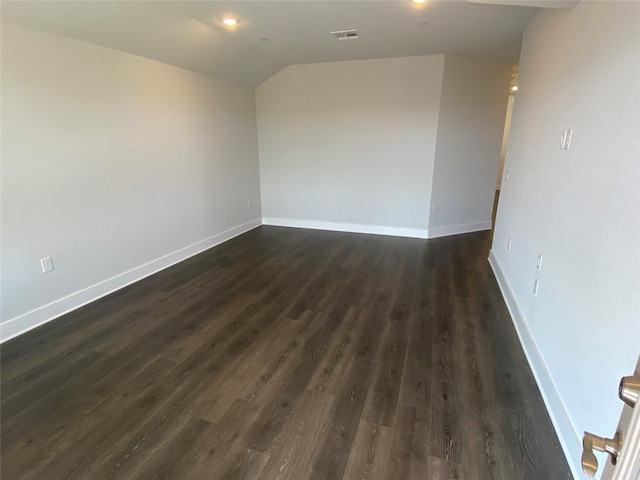 unfurnished room featuring lofted ceiling and dark hardwood / wood-style flooring