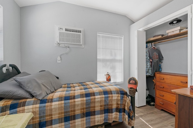 bedroom with vaulted ceiling, light hardwood / wood-style flooring, a closet, and a wall mounted AC