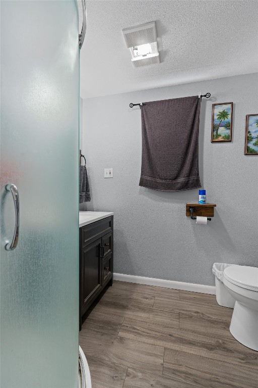 bathroom with hardwood / wood-style flooring, toilet, vanity, and a textured ceiling