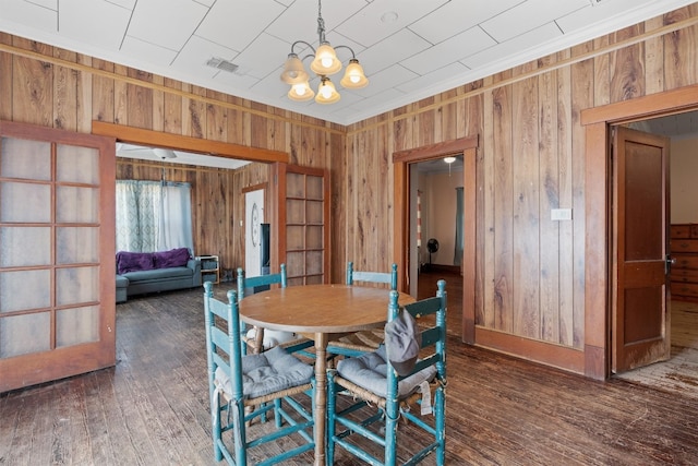 dining room with wood walls, dark hardwood / wood-style flooring, and a chandelier