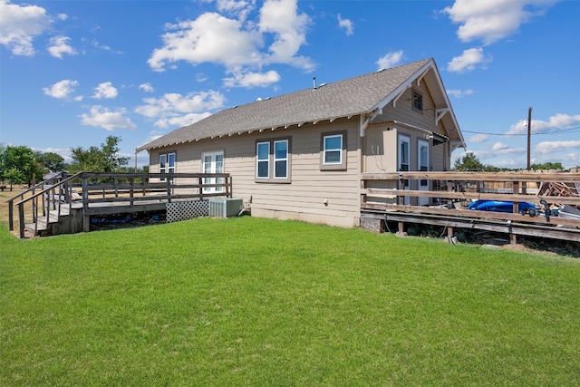 rear view of house with a yard, a wooden deck, and central AC