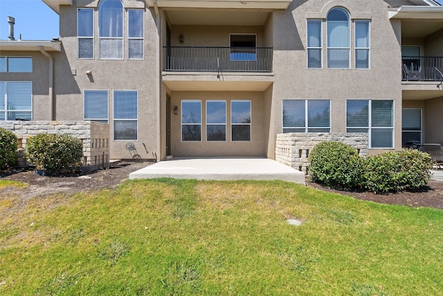 rear view of house featuring a balcony, a lawn, and a patio