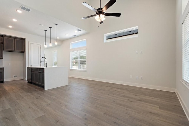 kitchen featuring visible vents, baseboards, light countertops, wood finished floors, and a sink