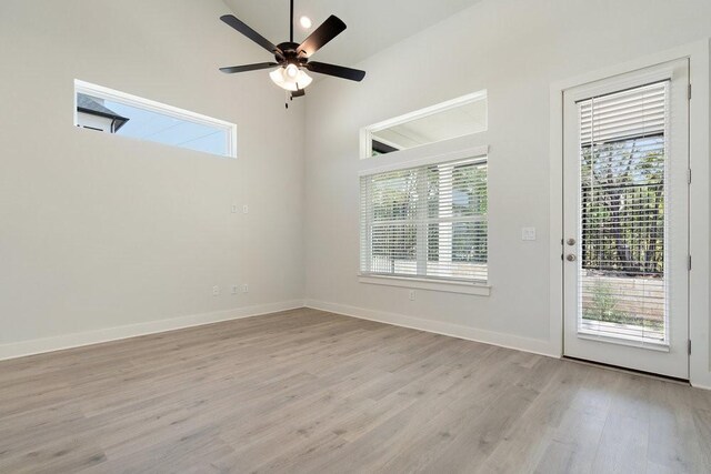 spare room with light wood-type flooring, baseboards, a healthy amount of sunlight, and a ceiling fan