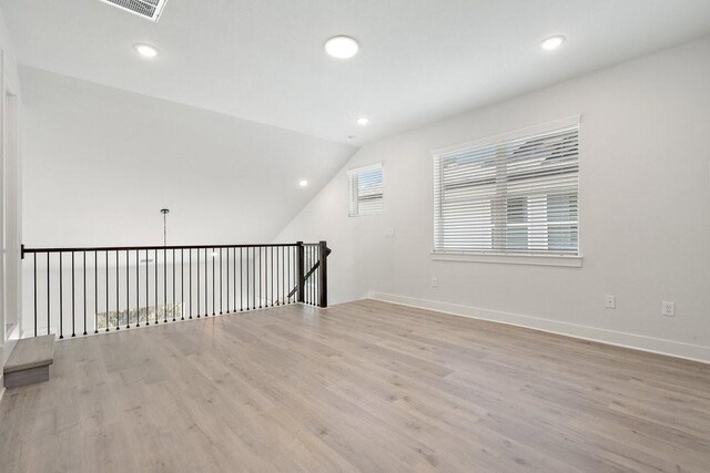 unfurnished room with recessed lighting, baseboards, lofted ceiling, and light wood finished floors