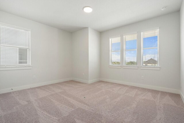 spare room with light carpet and baseboards