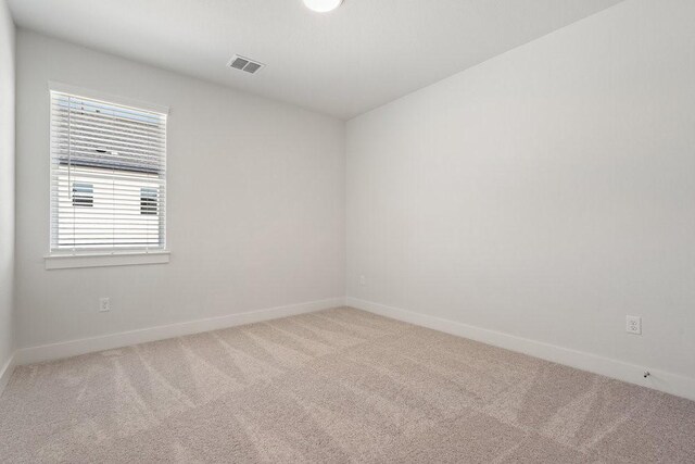 unfurnished room with visible vents, light colored carpet, and baseboards