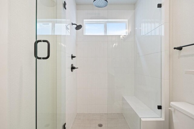 bathroom featuring toilet and a stall shower