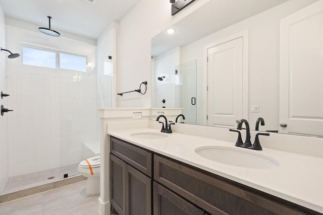 full bathroom featuring double vanity, a shower stall, toilet, and a sink