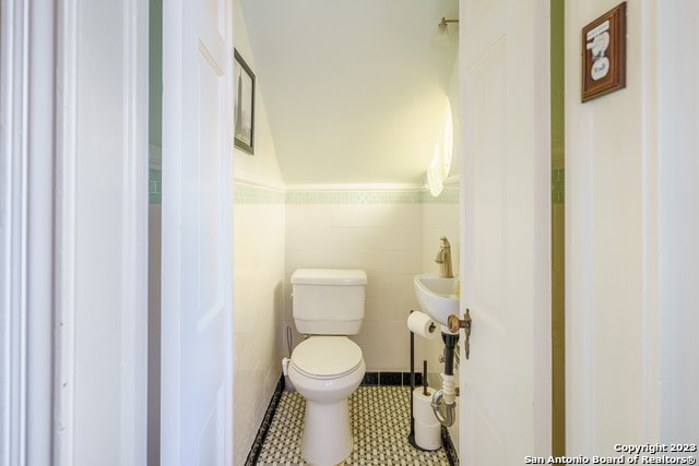 bathroom featuring tile floors, toilet, and tile walls