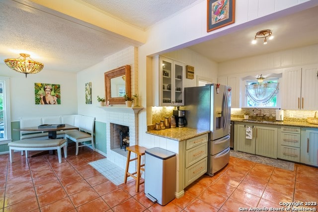 kitchen with a textured ceiling, backsplash, and a brick fireplace