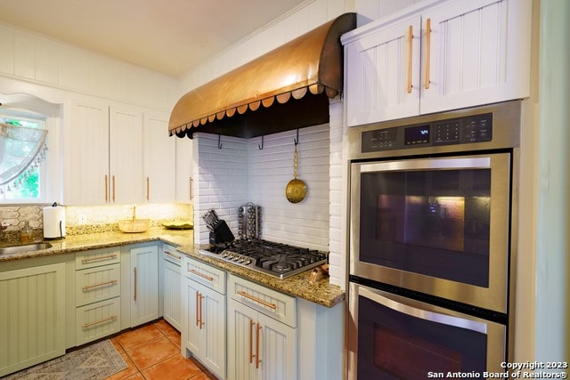 kitchen with white cabinets, tasteful backsplash, dark stone countertops, and appliances with stainless steel finishes