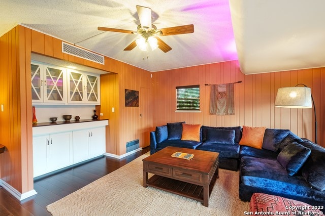 living room with wood walls, ceiling fan, and hardwood / wood-style flooring