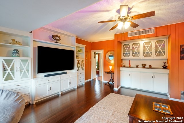 living room with dark hardwood / wood-style flooring, a textured ceiling, and ceiling fan