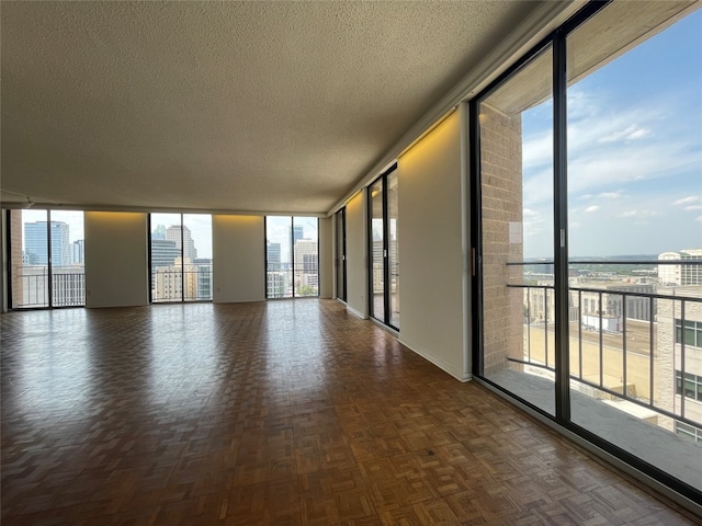 spare room with dark parquet flooring, a textured ceiling, and expansive windows