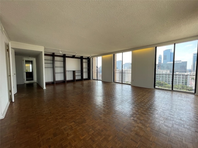 empty room with a textured ceiling, dark parquet flooring, and floor to ceiling windows