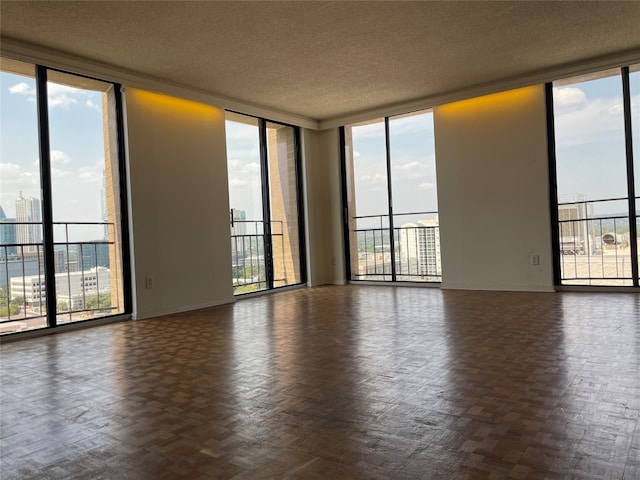 unfurnished room featuring floor to ceiling windows, dark parquet flooring, and a textured ceiling