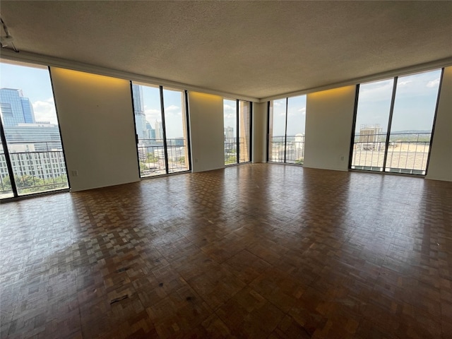 unfurnished room featuring plenty of natural light, floor to ceiling windows, and dark parquet flooring