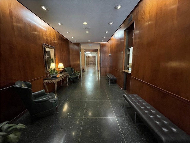 corridor featuring wooden walls and dark tile floors