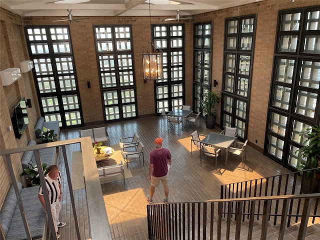 interior space with beamed ceiling, ceiling fan with notable chandelier, dark wood-type flooring, and a high ceiling